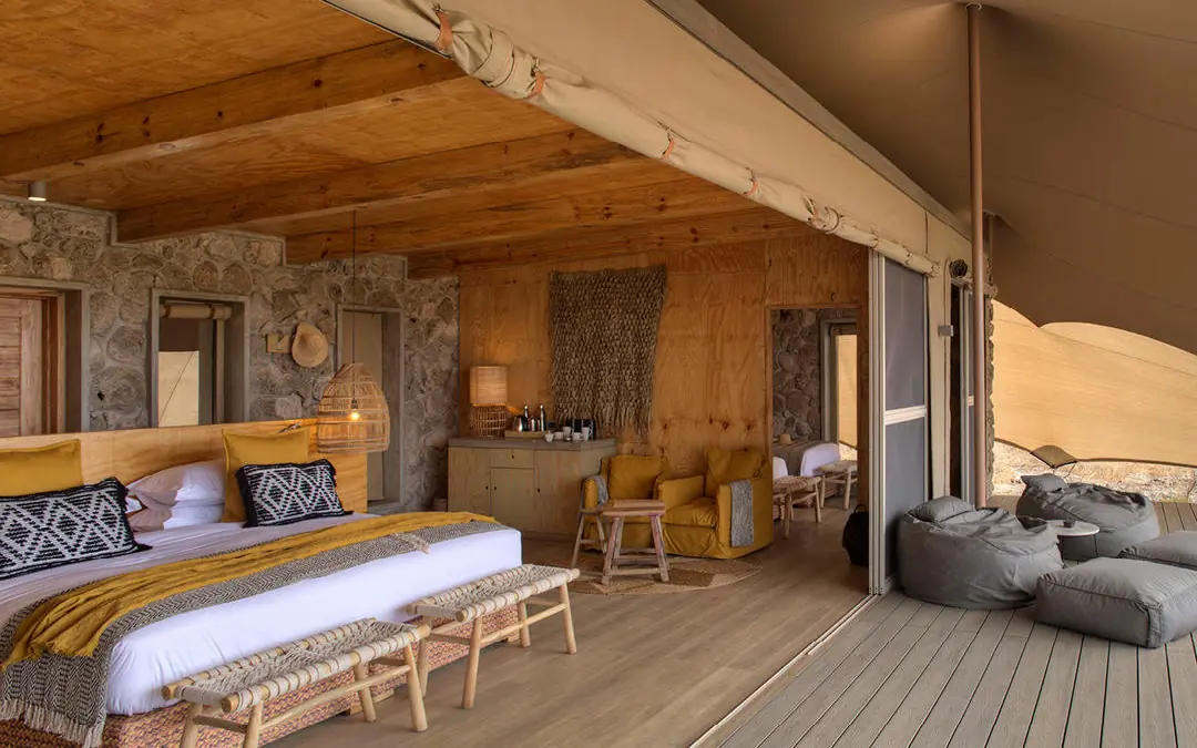 Spacious safari tent bedroom with wooden beams and deck, Namiri Plains, Serengeti National Park, Tanzania