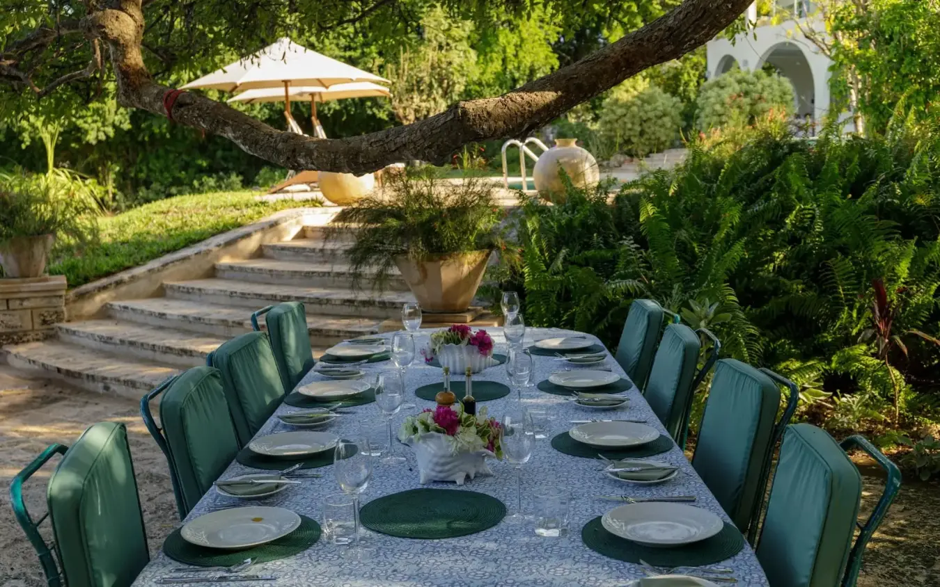 Outdoor dining table set for dinner in lush garden with stone terrace, Nderit House, Kilifi, Kenya