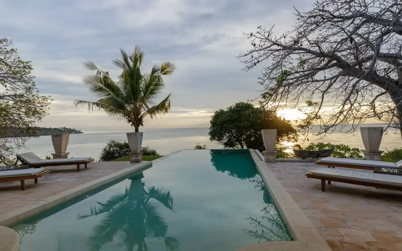 Infinity pool with palm tree reflection at sunset overlooking coastal waters, Nderit House, Kilifi, Kenya