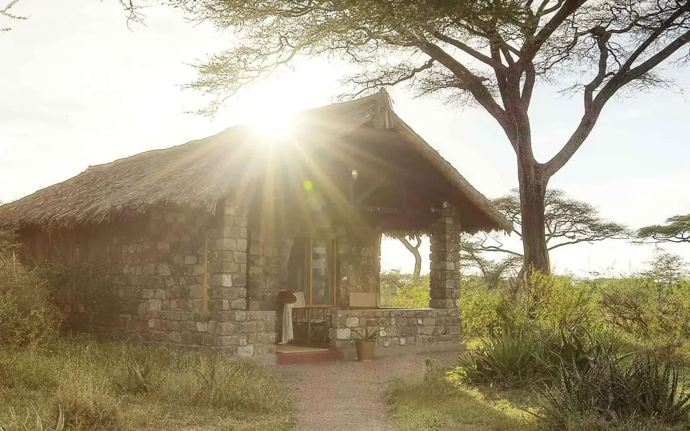 Stone bungalow with thatched roof at sunrise, Ndutu Safari Lodge, Serengeti National Park, Tanzania