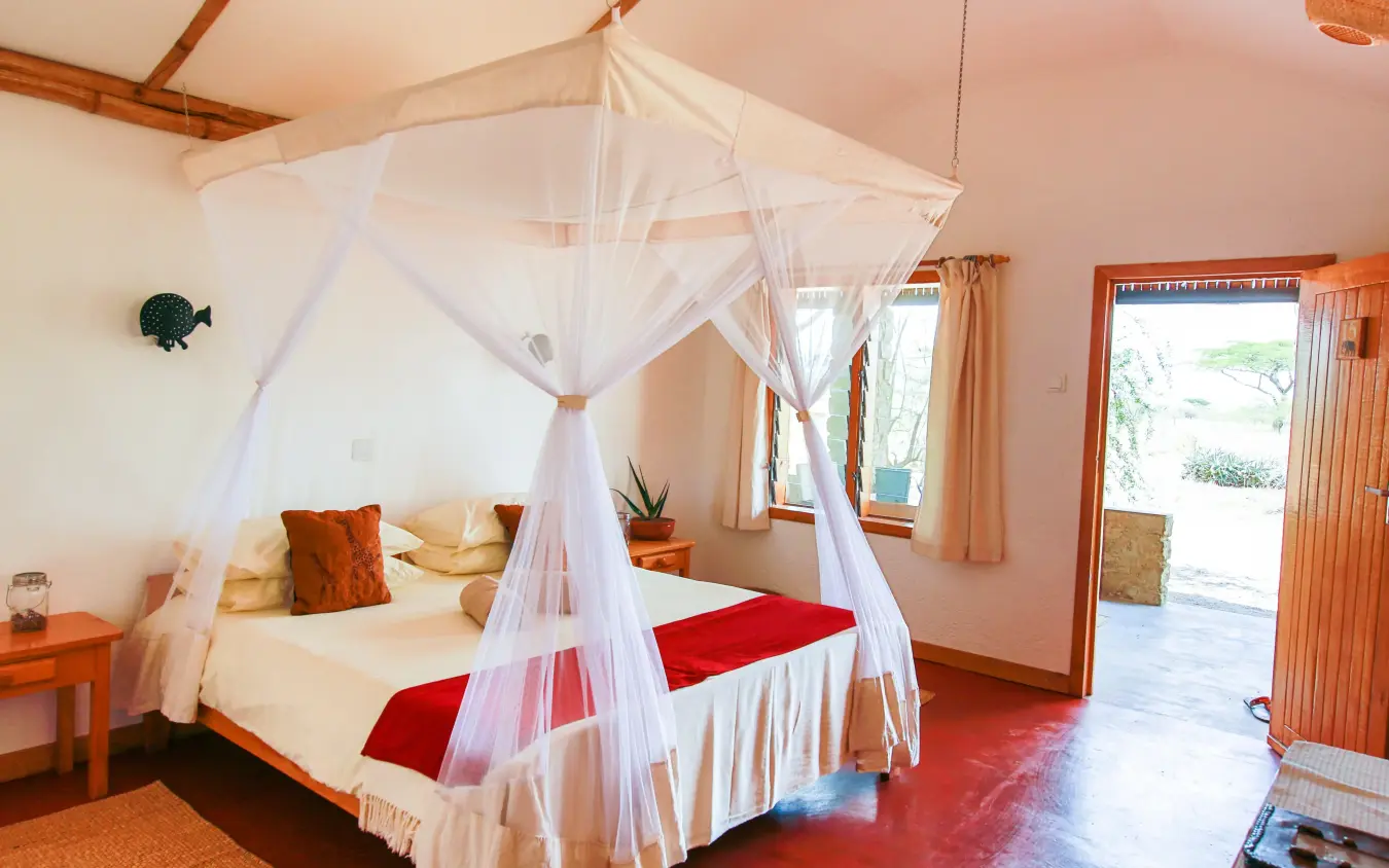 Spacious bedroom with white canopy bed and red accents, Ndutu Safari Lodge, Serengeti National Park, Tanzania