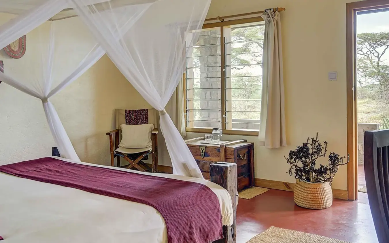 Bedroom with four-poster canopy bed and large windows, Ndutu Safari Lodge, Serengeti National Park, Tanzania