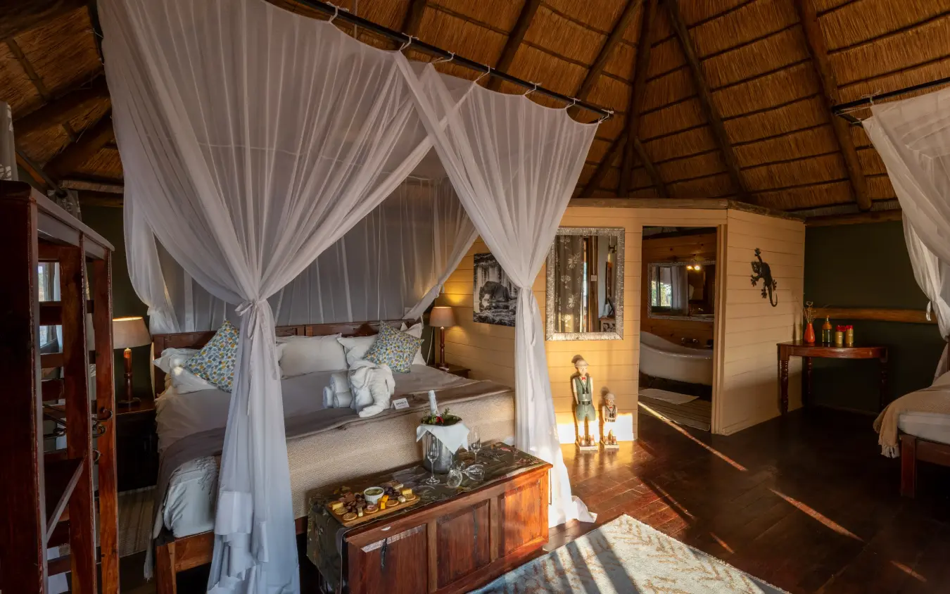 Luxury safari lodge bedroom with four-poster canopy bed and en-suite bathroom, Nehimba Lodge, Hwange National Park, Zimbabwe