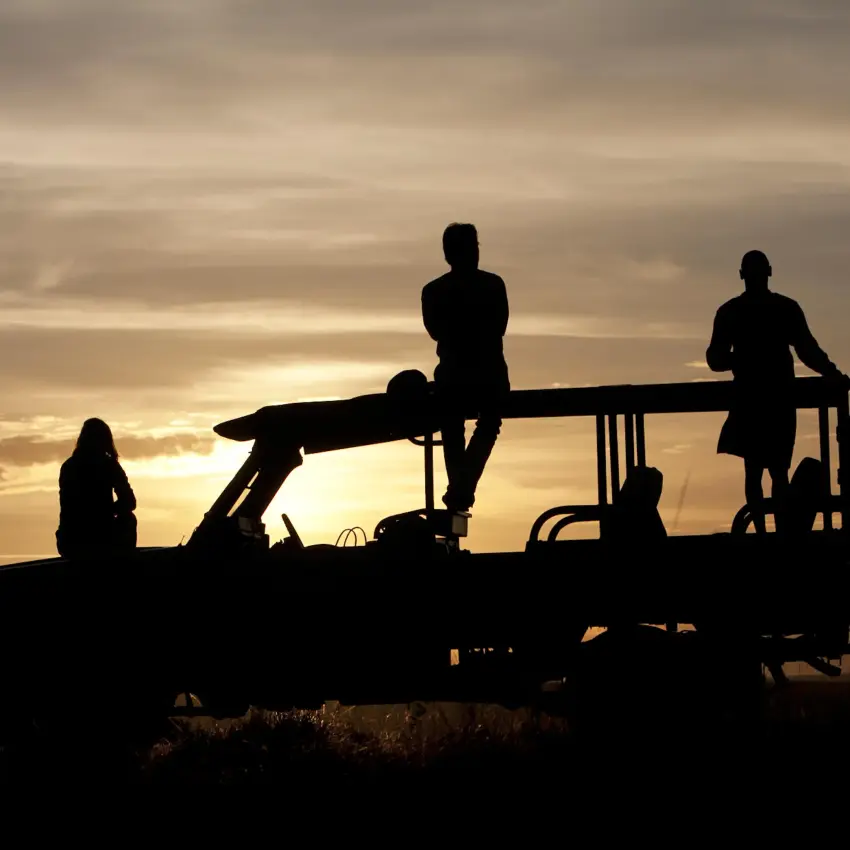 Silhouetted guests on open safari vehicle at sunset, Ngare Serian, Maasai Mara, Kenya