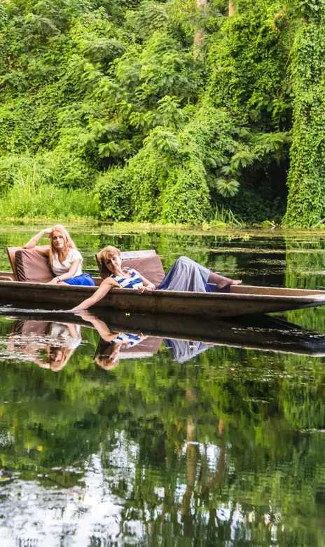 Guests paddling traditional wooden canoe on calm river, Ngare Sero Mountain Lodge, Arusha, Tanzania