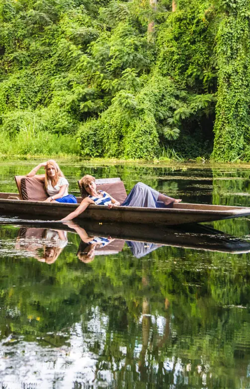 Guests paddling traditional wooden canoe on calm river, Ngare Sero Mountain Lodge, Arusha, Tanzania