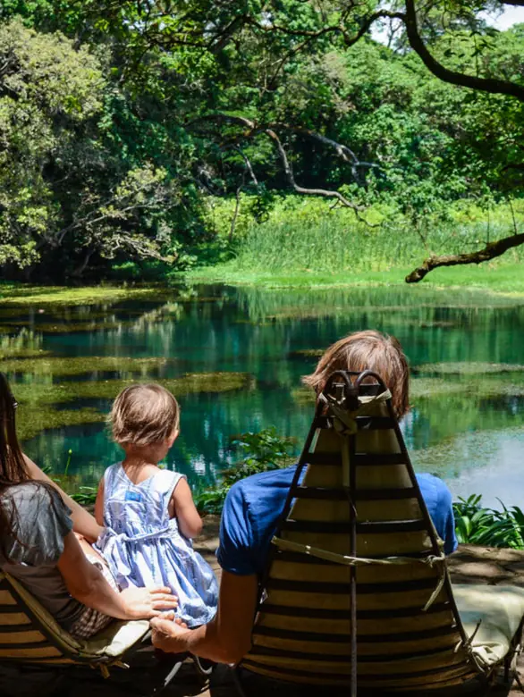 Family relaxing in chairs overlooking tranquil river, Ngare Sero Mountain Lodge, Arusha, Tanzania