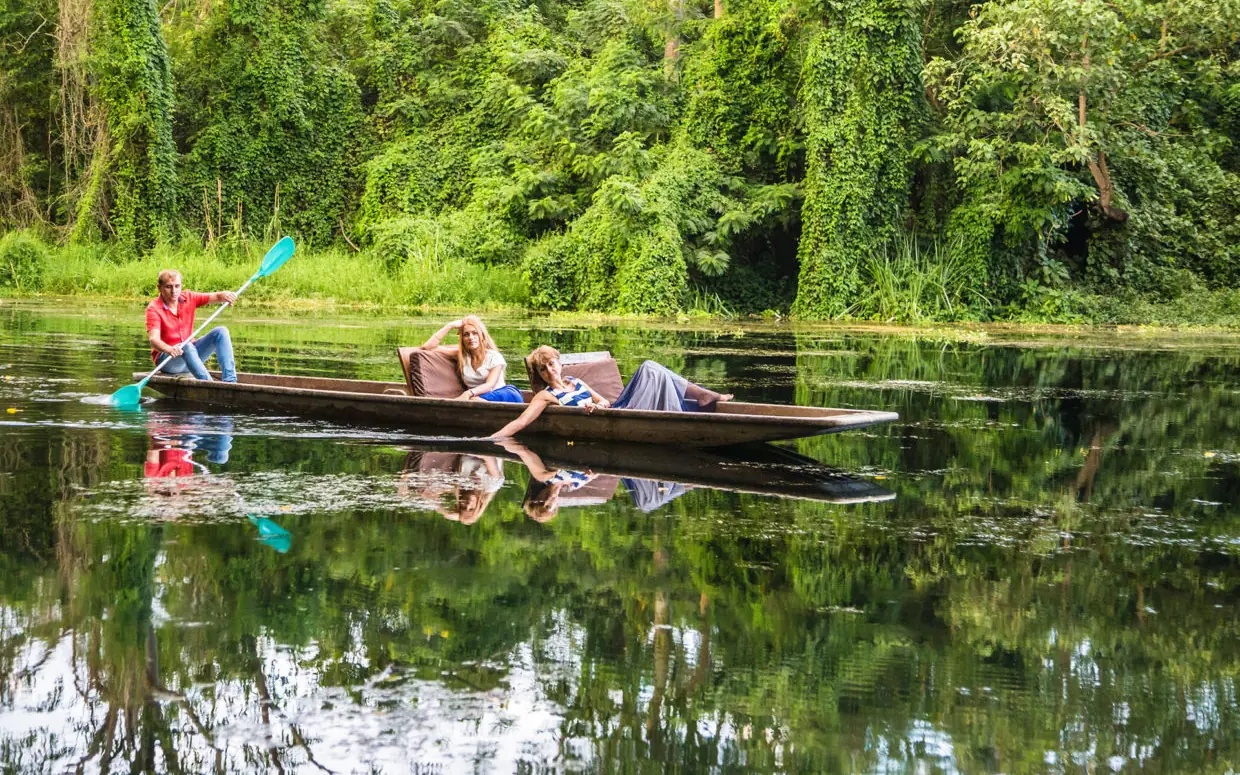 Guests paddling traditional wooden canoe on calm river, Ngare Sero Mountain Lodge, Arusha, Tanzania