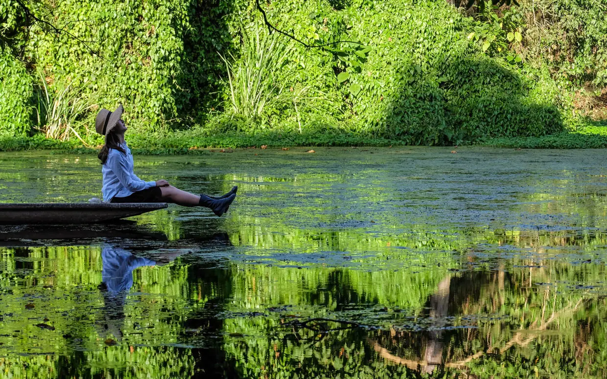 Guest relaxing on log overlooking calm river, Ngare Sero Mountain Lodge, Arusha, Tanzania