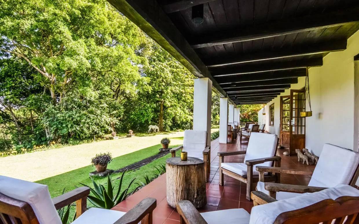 Covered veranda with lounge chairs overlooking manicured grounds, Ngare Sero Mountain Lodge, Arusha, Tanzania