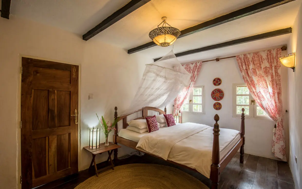 Bedroom with four-poster bed and red patterned curtains, Ngare Sero Mountain Lodge, Arusha, Tanzania