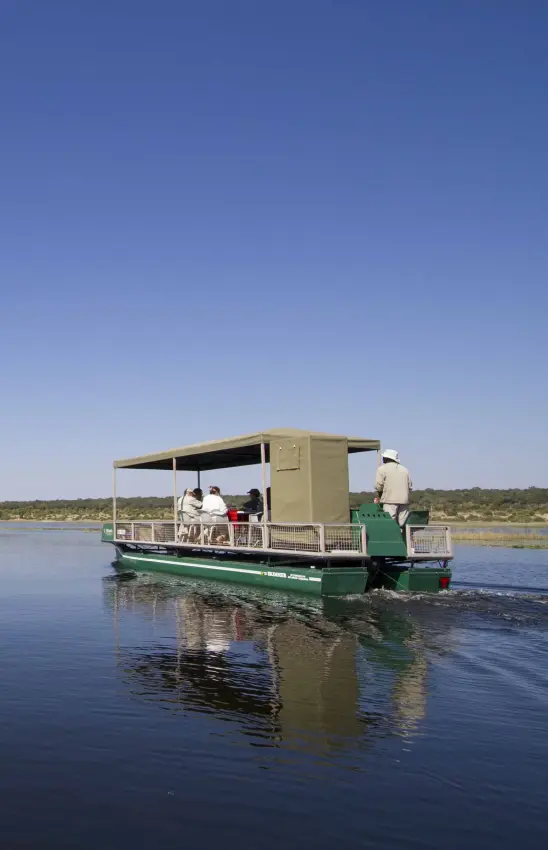 Game viewing boat with passengers on river in wildlife habitat, Ngoma Safari Lodge, Chobe, Botswana