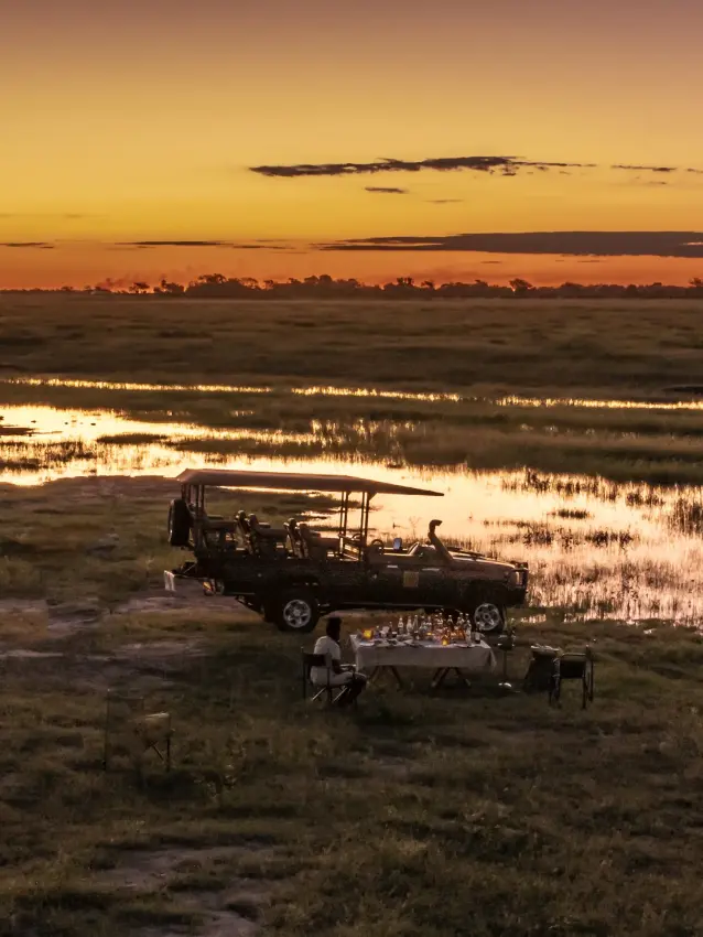 Safari vehicle parked by wetland at sunset with guests on viewing platform, Ngoma Safari Lodge, Chobe, Botswana