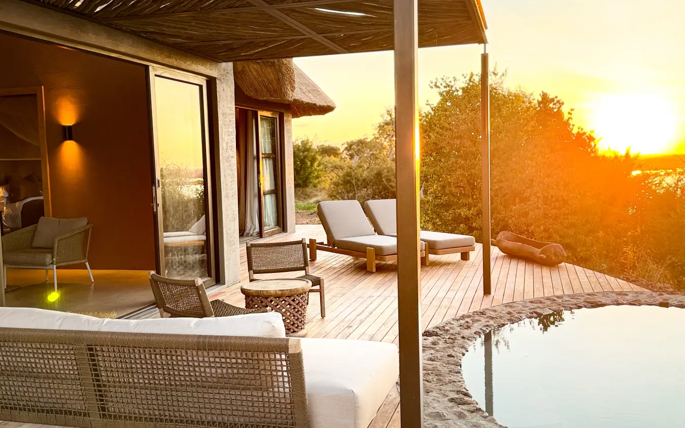 Modern lodge deck with lounge chairs overlooking savanna at sunset, Ngoma Safari Lodge, Chobe, Botswana