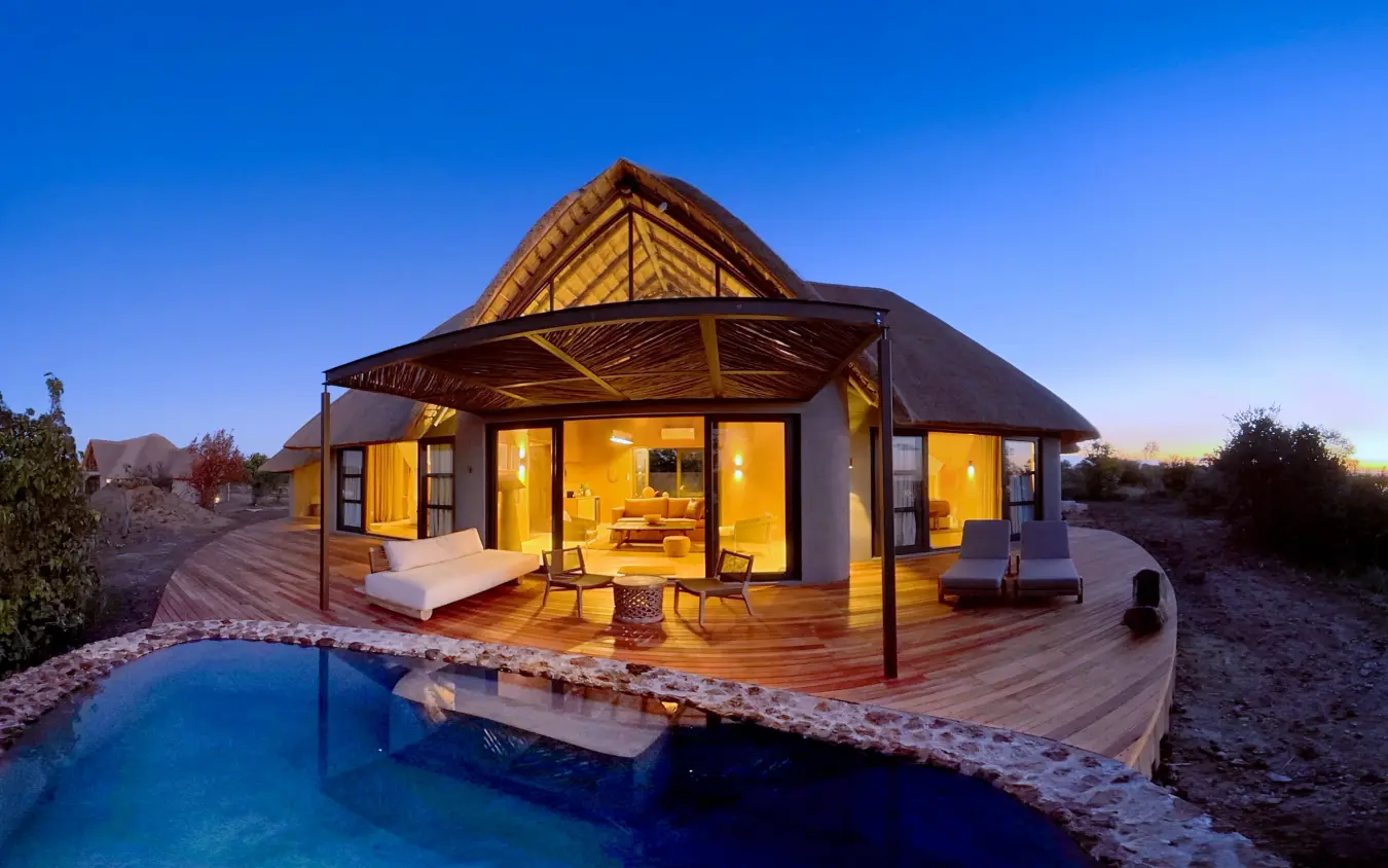 Luxury safari lodge with illuminated interior and private pool at dusk, Ngoma Safari Lodge, Chobe, Botswana
