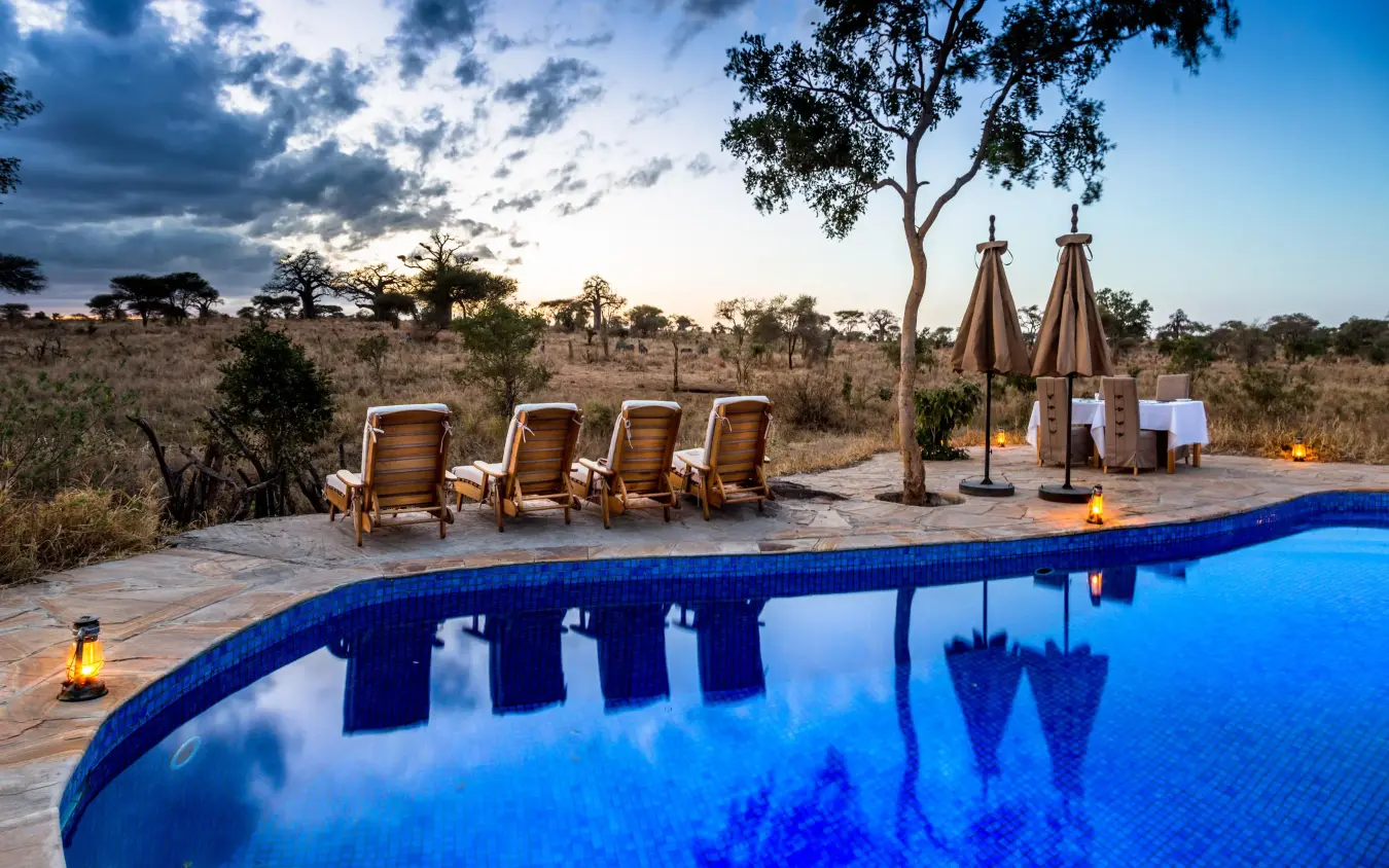 Swimming pool at dusk with lounge chairs and savanna backdrop, Nimali Tarangire, Tarangire National Park, Tanzania