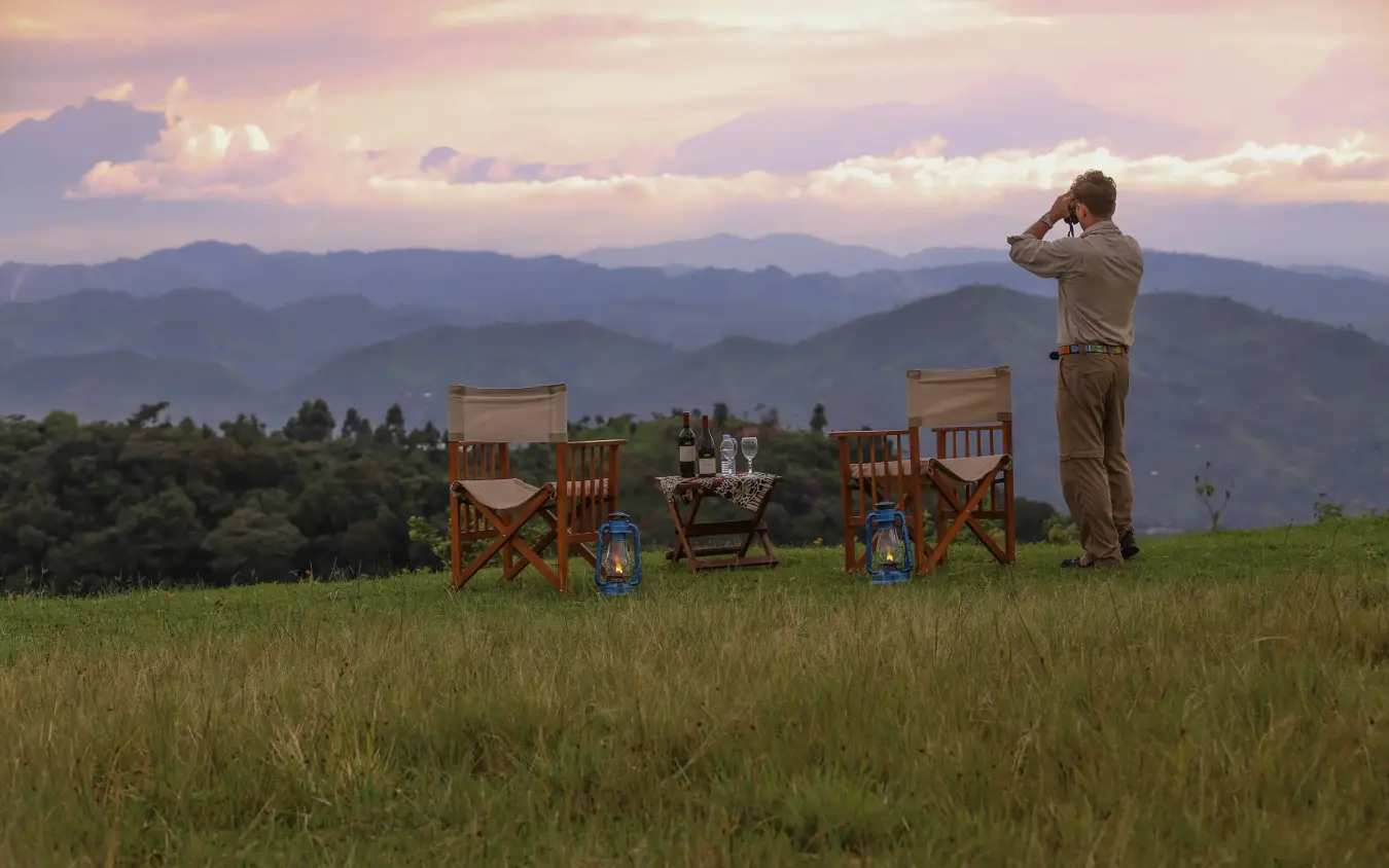 Guide observing landscape from safari chairs at sunset, Nkuringo Gorilla Lodge, Bwindi Impenetrable Forest, Uganda