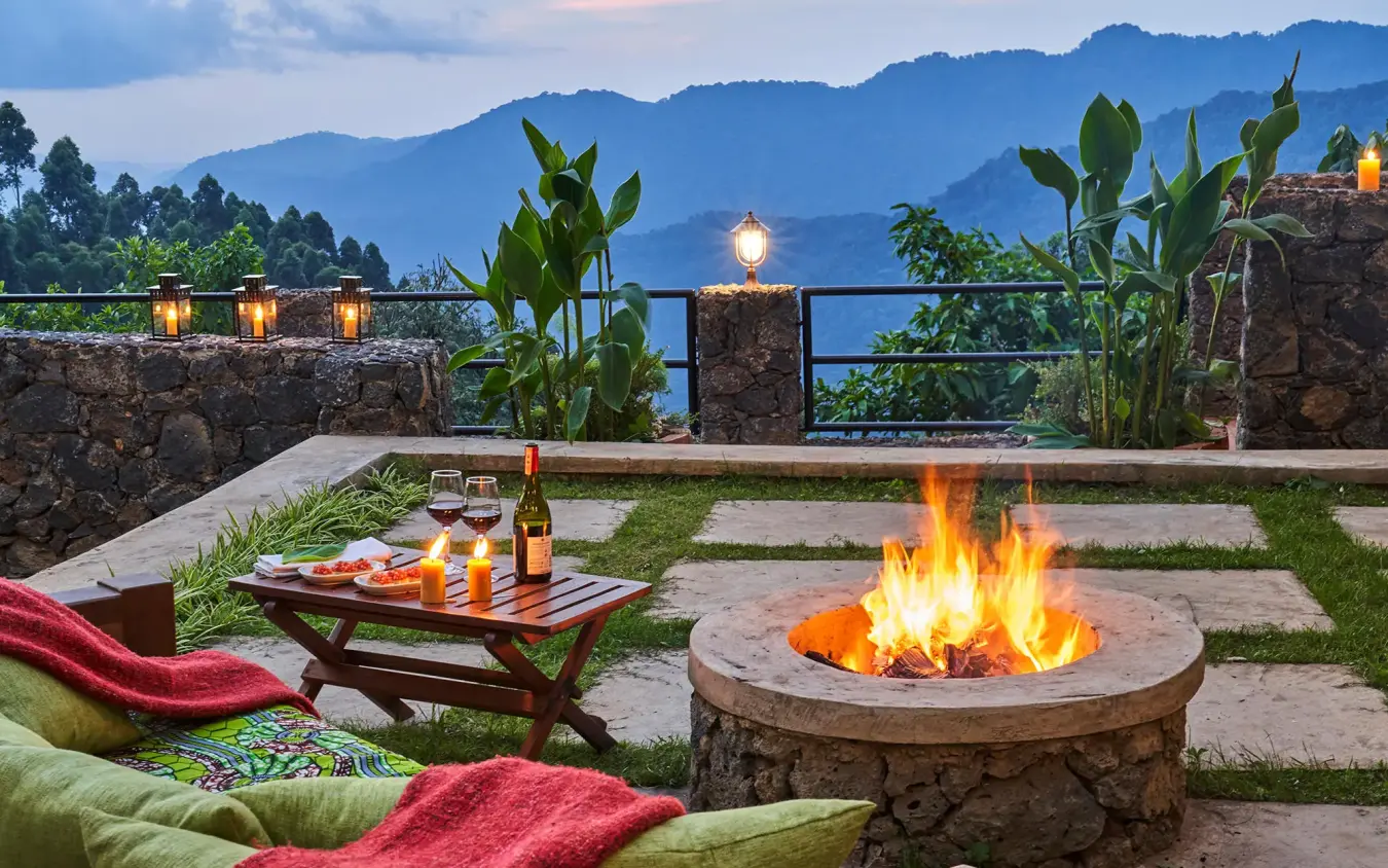 Evening firepit gathering with mountain views and hanging lanterns, Nkuringo Gorilla Lodge, Bwindi Impenetrable Forest, Uganda