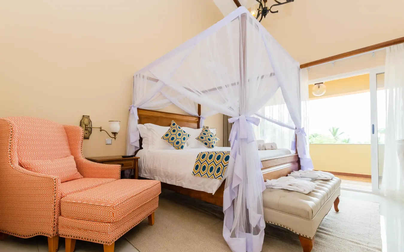 Bedroom with canopy bed, orange armchair, and balcony view, No.5 Boutique Hotel, Entebbe and Kampala, Uganda