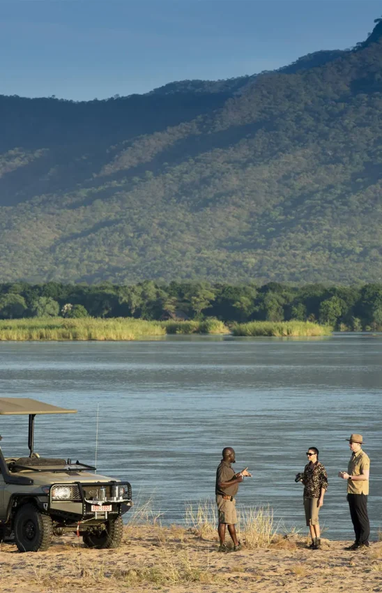 Safari vehicle parked on riverbank with guides and guests, Nyamatusi Camp, Mana Pools, Zimbabwe