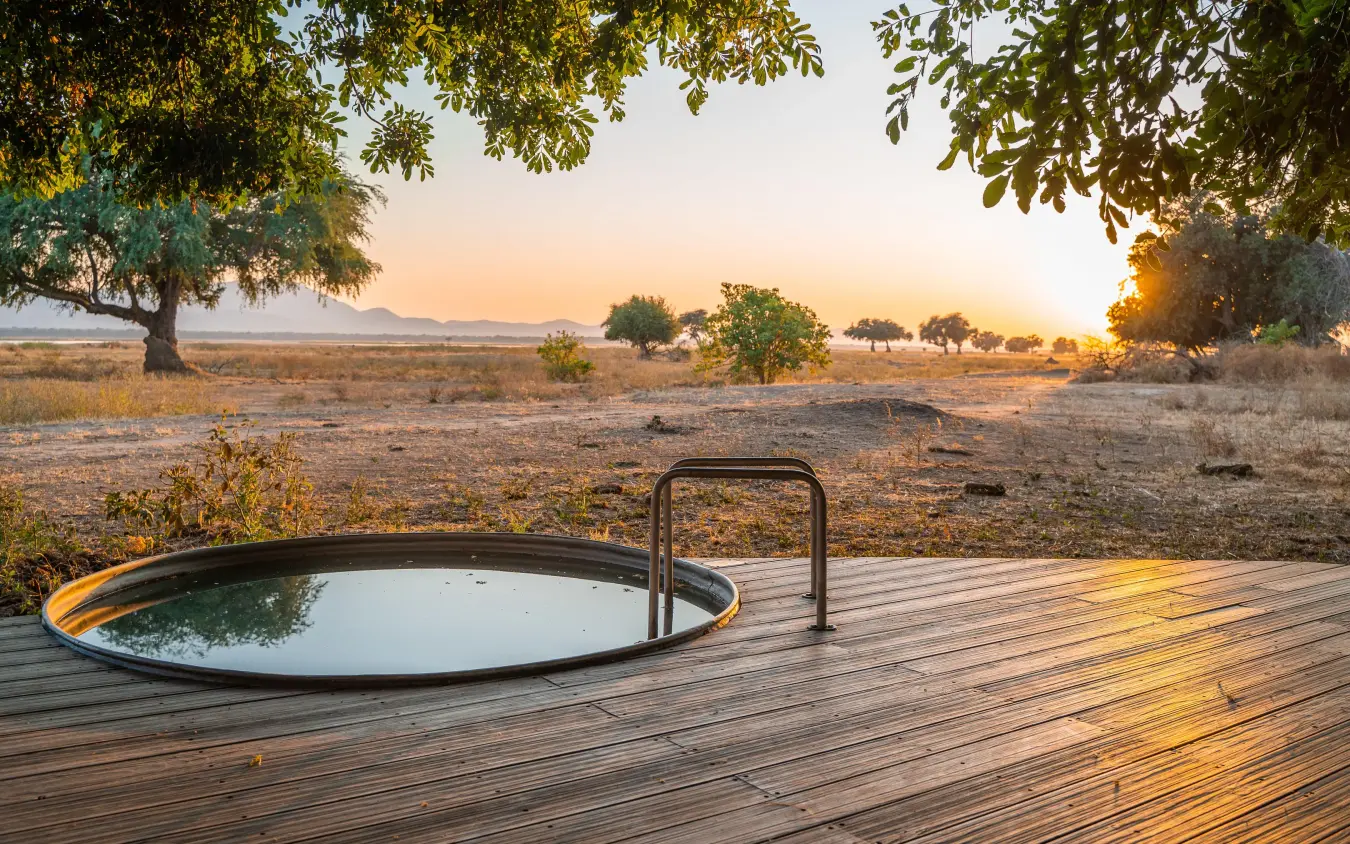 Outdoor bathtub on wooden deck overlooking savanna at sunset, Nyamatusi Camp, Mana Pools, Zimbabwe