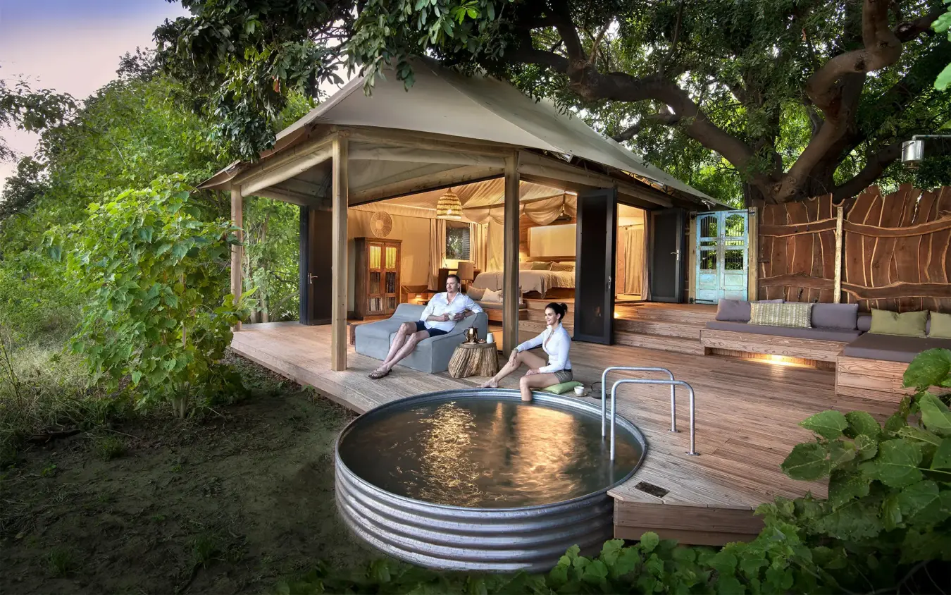 Guest relaxing on wooden deck outside safari lodge, Nyamatusi Camp, Mana Pools, Zimbabwe