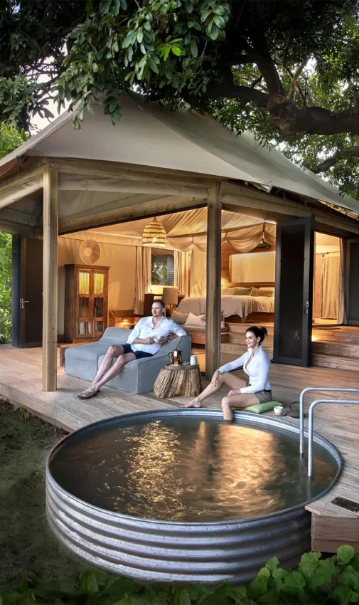 Guest relaxing on wooden deck outside safari lodge, Nyamatusi Camp, Mana Pools, Zimbabwe