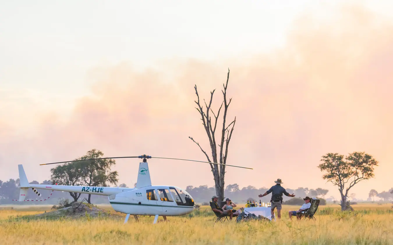 Helicopter landing in grassland savanna with guides and equipment