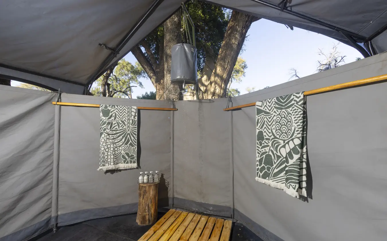 Open-air bathroom with wooden decking and patterned towels, Kweene Trails, The Okavango Delta, Botswana