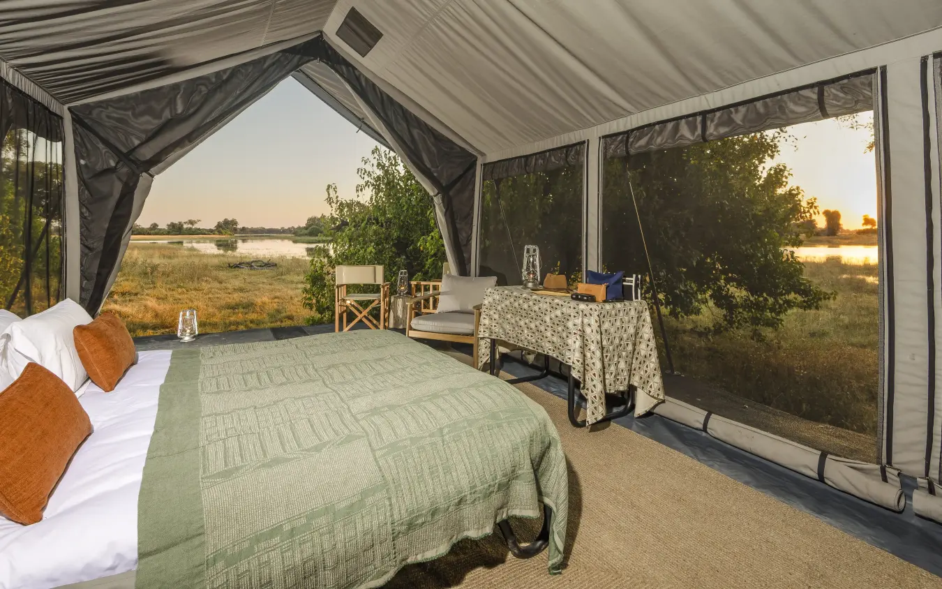 Bedroom tent with bed overlooking wetland landscape at sunset, Kweene Trails, The Okavango Delta, Botswana