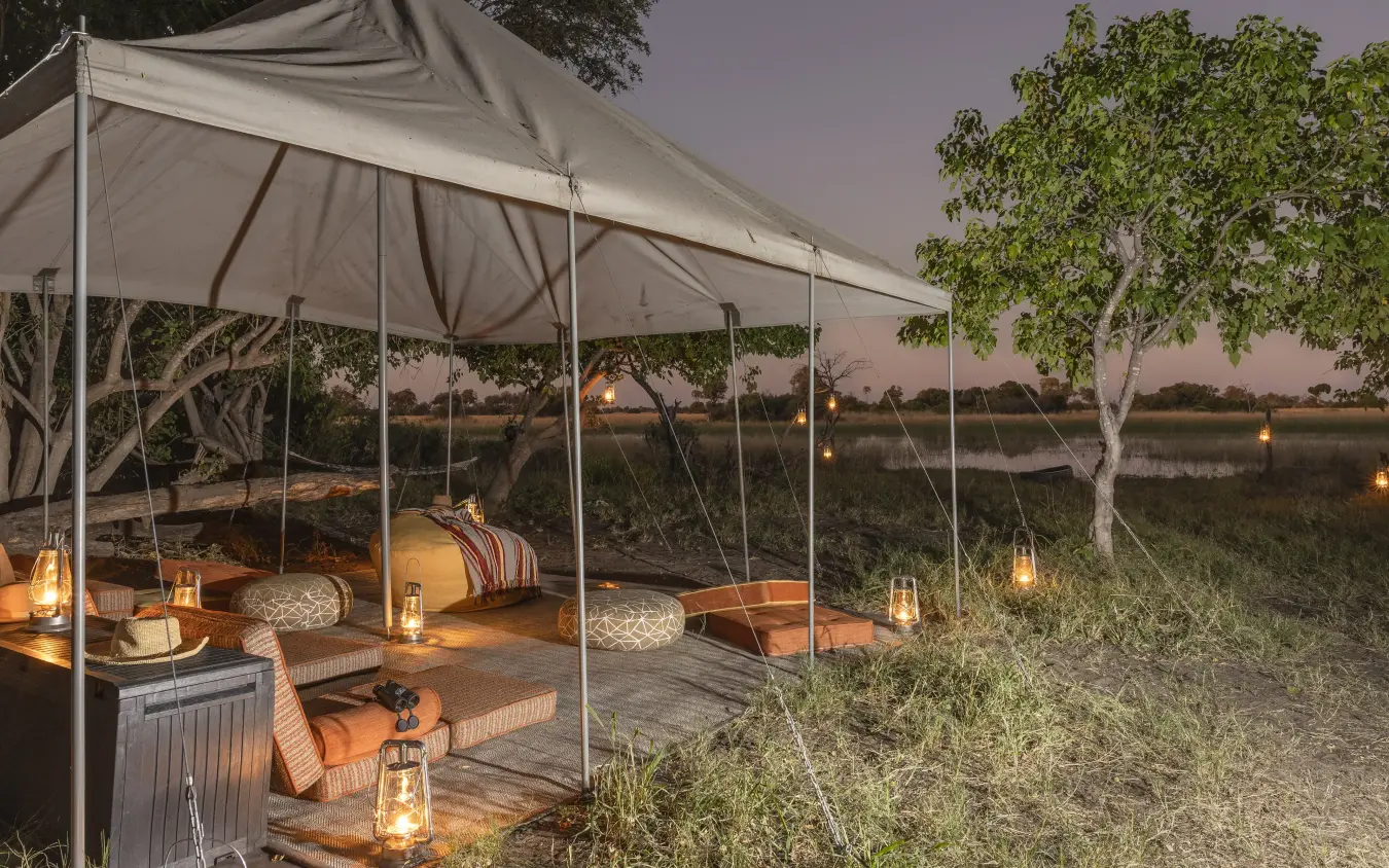 Canvas tent lounge with waterside view at dusk, Kweene Trails, The Okavango Delta, Botswana