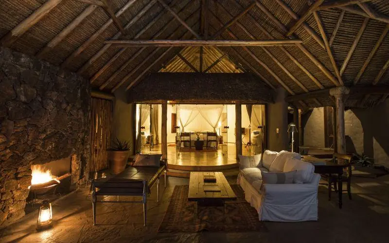Interior view of open-air lounge with fireplace at night, Ol Donyo Lodge, Amboseli and Chyulu Hills, Kenya