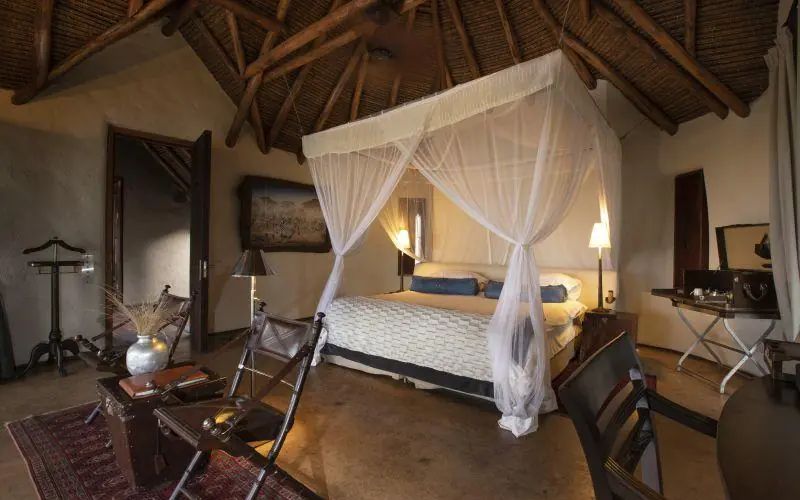 Spacious bedroom with four-poster canopy bed and wooden beams, Ol Donyo Lodge, Amboseli and Chyulu Hills, Kenya