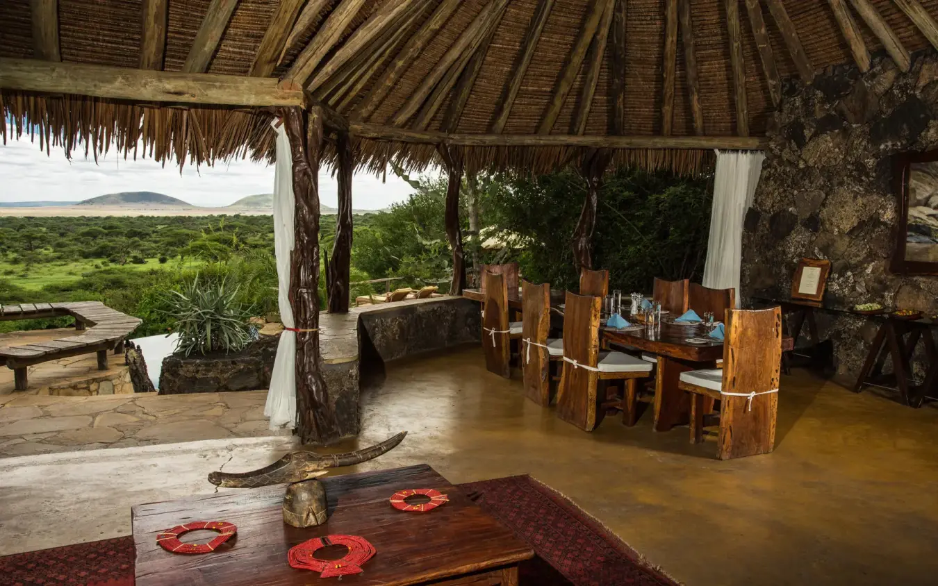 Open-air lounge with thatched roof overlooking green landscape, Ol Donyo Lodge, Amboseli and Chyulu Hills, Kenya