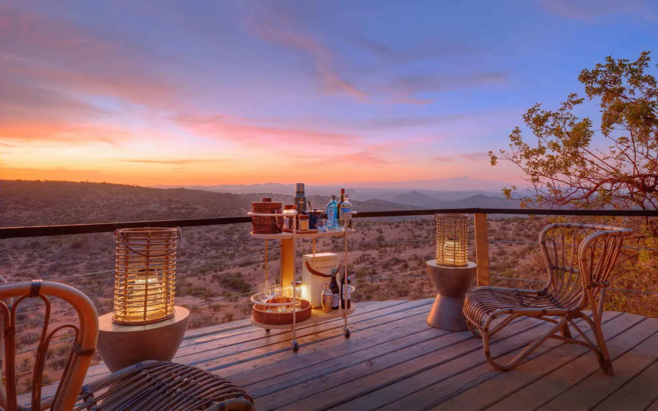 Wooden deck overlooking vast savanna at sunset with furniture, Ol Lentille, Laikipia Highlands, Kenya