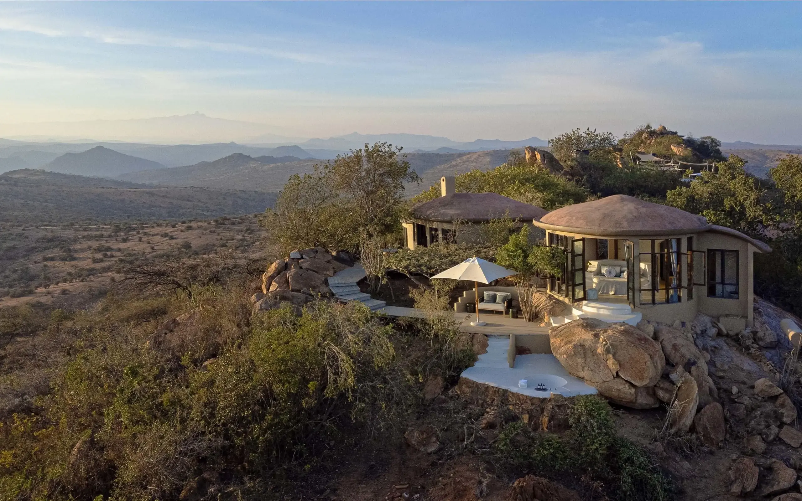 Curved modern lodge buildings perched on rocky hilltop overlooking valley, Ol Lentille, Laikipia Highlands, Kenya