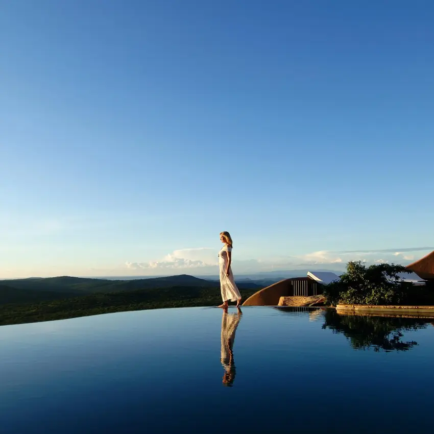 Woman standing by infinity pool overlooking landscape, Ol Lentille, Laikipia Highlands, Kenya