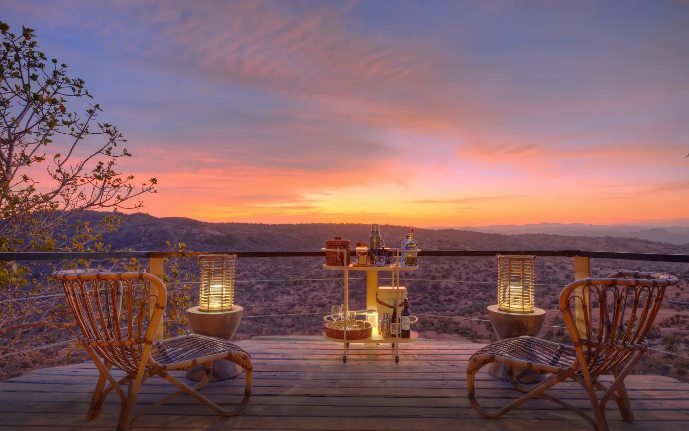 Wooden chairs on deck overlooking savanna landscape at sunset, Ol Lentille, Laikipia Highlands, Kenya