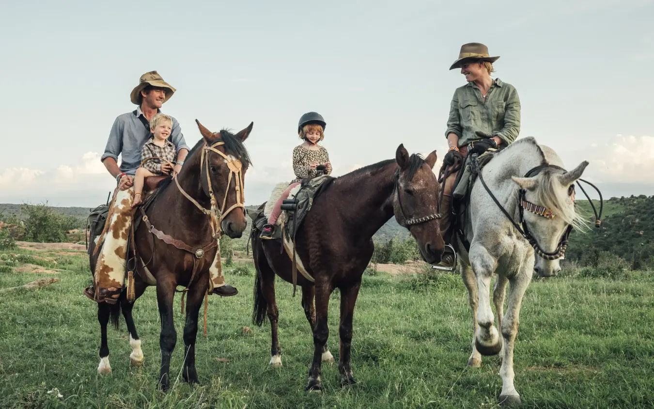 Family horseback riding across open grassland plains, Ol Malo Lodge, Laikipia Highlands, Kenya
