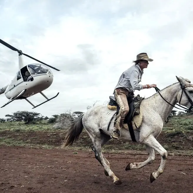 Cowboy on horseback with helicopter in background, Ol Malo Lodge, Laikipia Highlands, Kenya