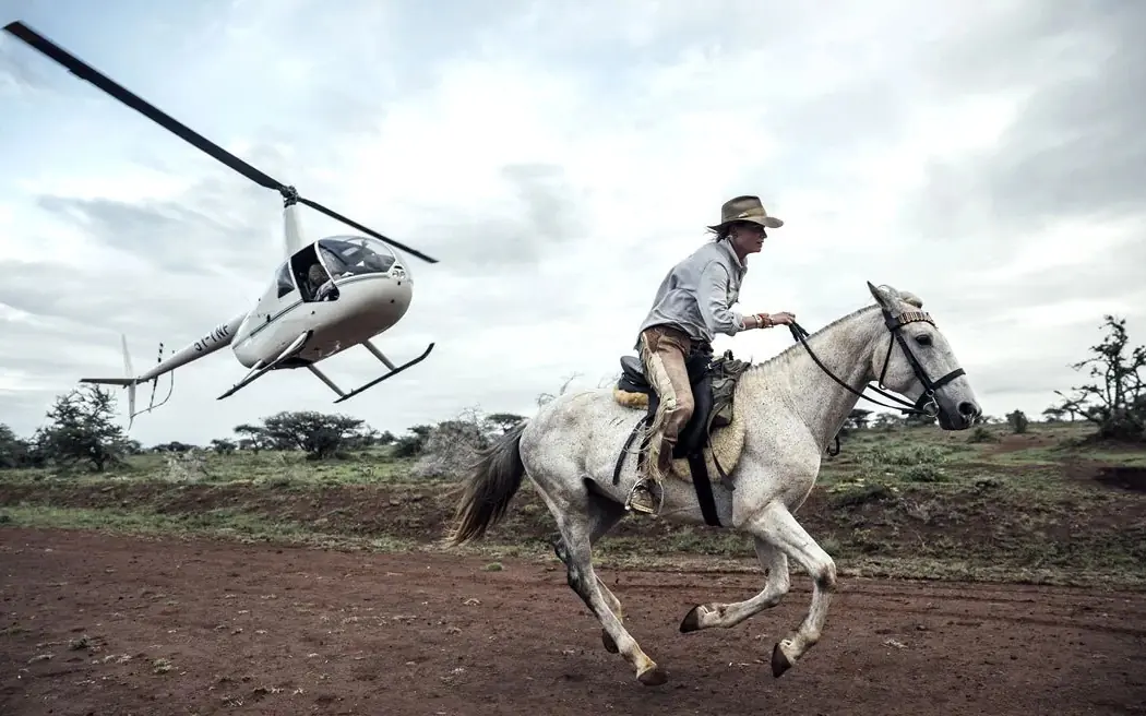 Cowboy on horseback with helicopter in background, Ol Malo Lodge, Laikipia Highlands, Kenya
