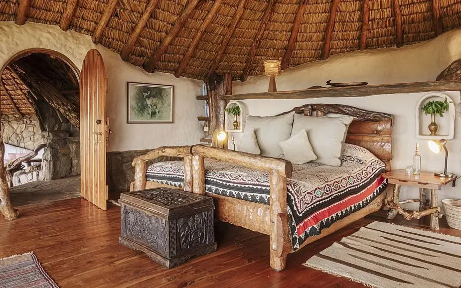 Circular thatched bedroom with wooden bed and rustic furnishings, Ol Malo Lodge, Laikipia Highlands, Kenya