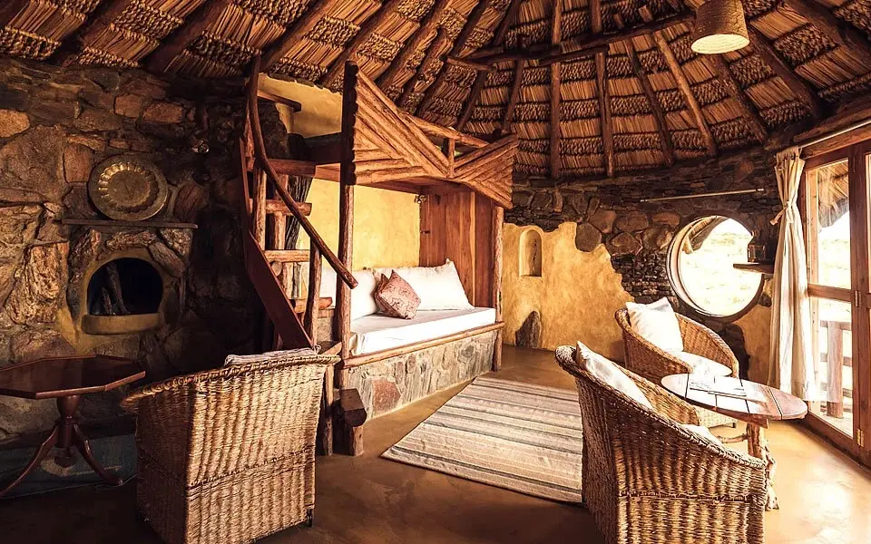 Rustic stone bedroom with thatched roof and wooden furnishings, Ol Malo Lodge, Laikipia Highlands, Kenya