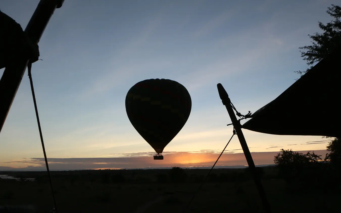 Hot air balloon silhouetted against sunrise sky, Olakira Migration Camp, Serengeti National Park, Tanzania