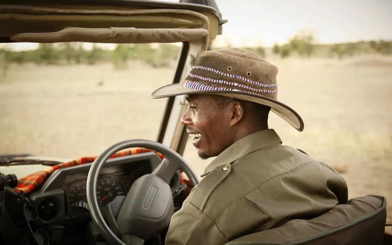 Safari guide driving open vehicle across African savanna, Olakira Migration Camp, Serengeti National Park, Tanzania