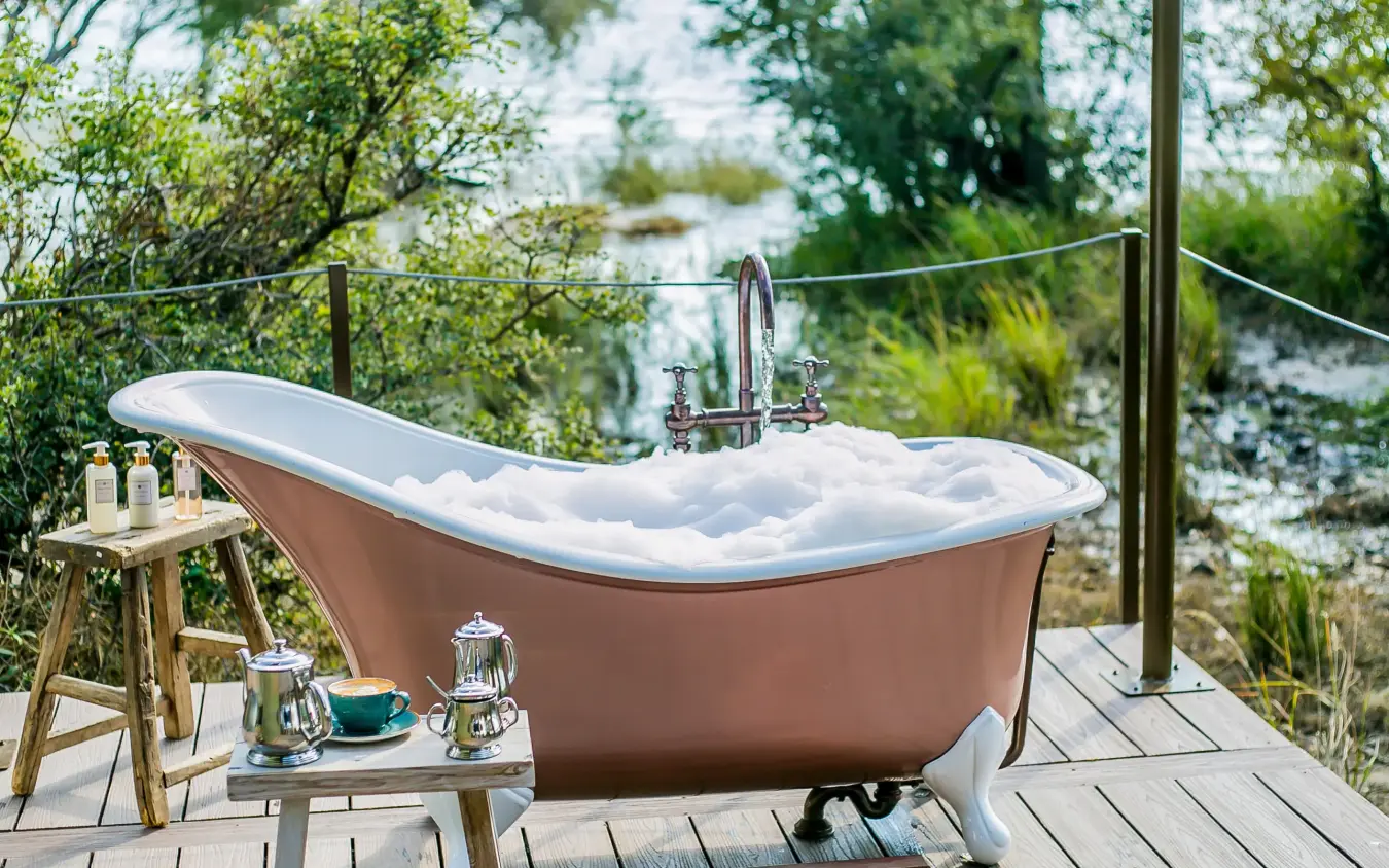 Outdoor bathtub on wooden deck overlooking water, Old Drift Lodge, Victoria Falls, Zimbabwe