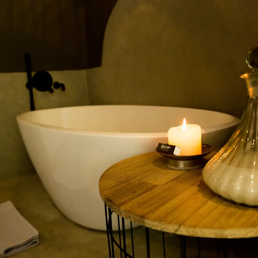 Luxury bathroom with freestanding bathtub, candlelit side table and decorative glass decanter, Olive Grove Guesthouse, Windhoek, Namibia