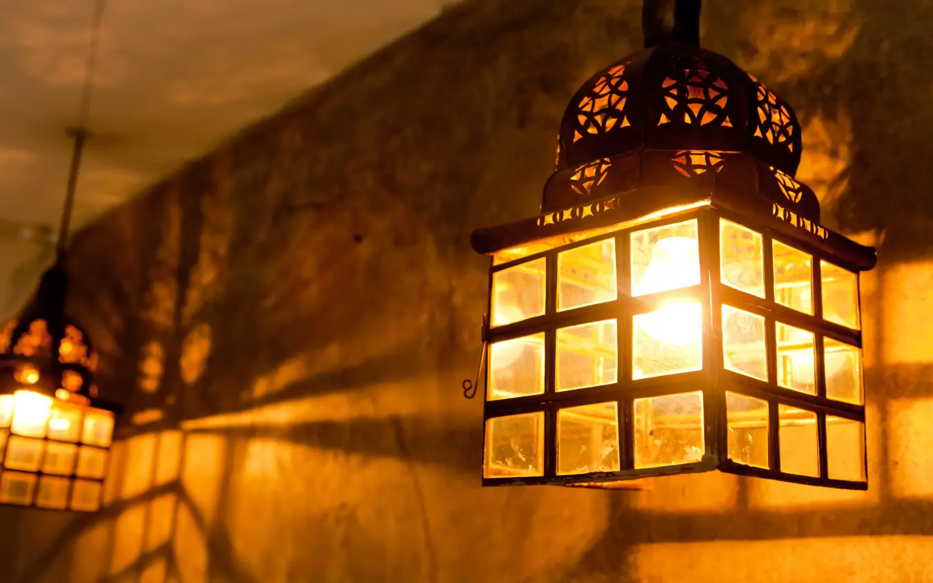 Lantern with geometric patterns casting shadows on ochre wall at dusk, Olive Grove Guesthouse, Windhoek, Namibia