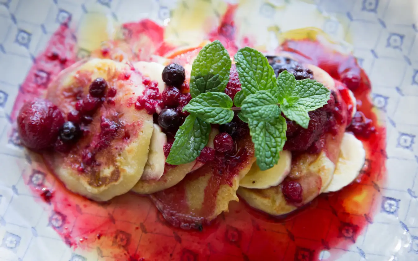 Gourmet pancakes with berry compote and fresh mint garnish on patterned plate, Olive Grove Guesthouse, Windhoek, Namibia