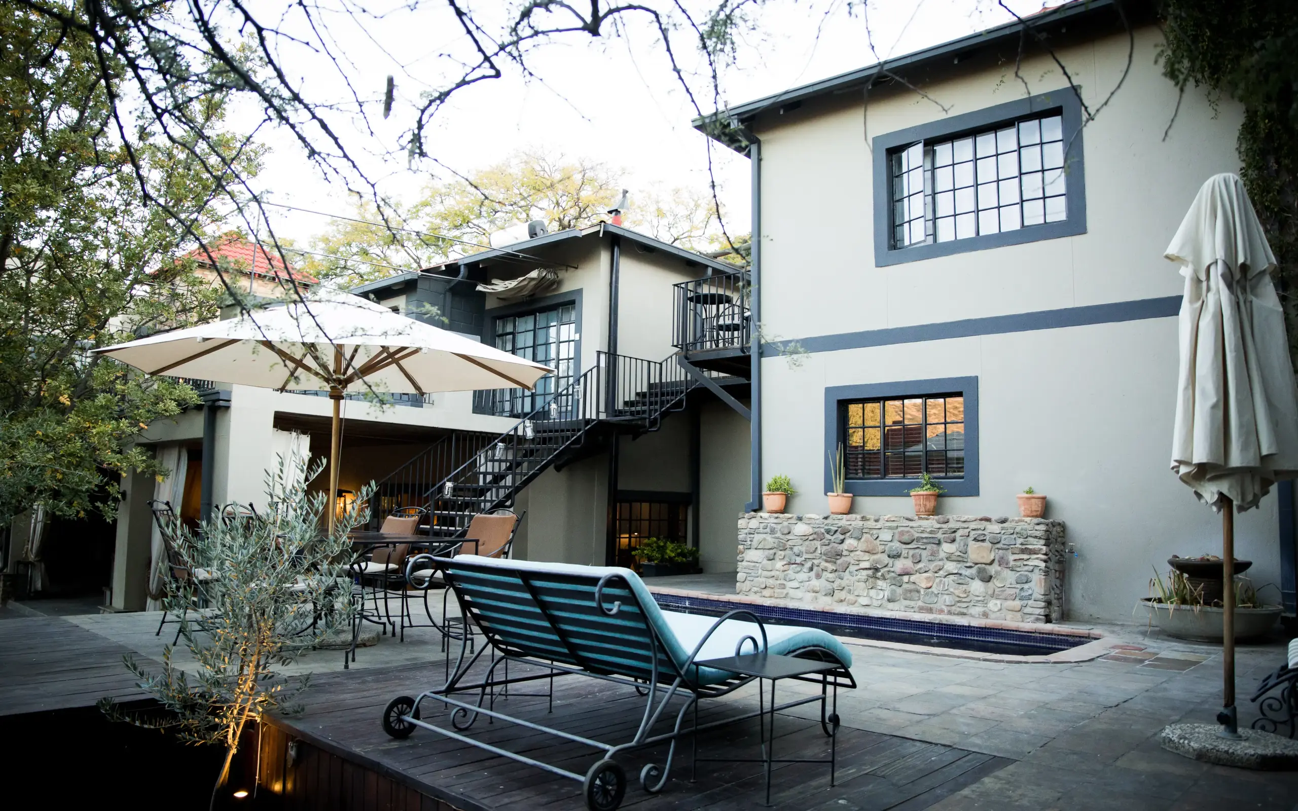 Courtyard with lounge chairs, umbrella and modern residential architecture, Olive Grove Guesthouse, Windhoek, Namibia